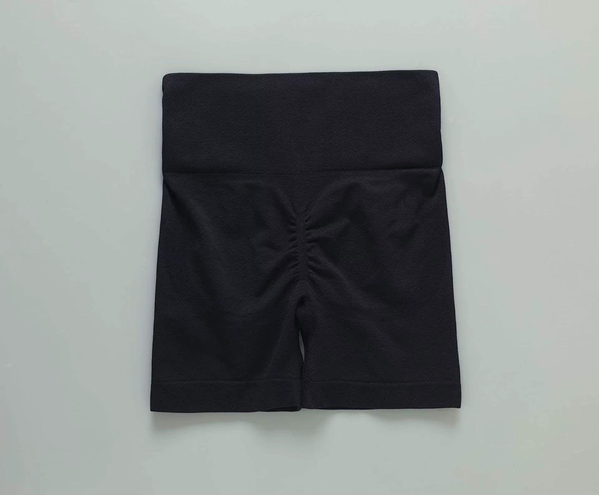 MotionMade black high-waisted workout shorts with ruched back detail for a push-up effect and compressive fit.