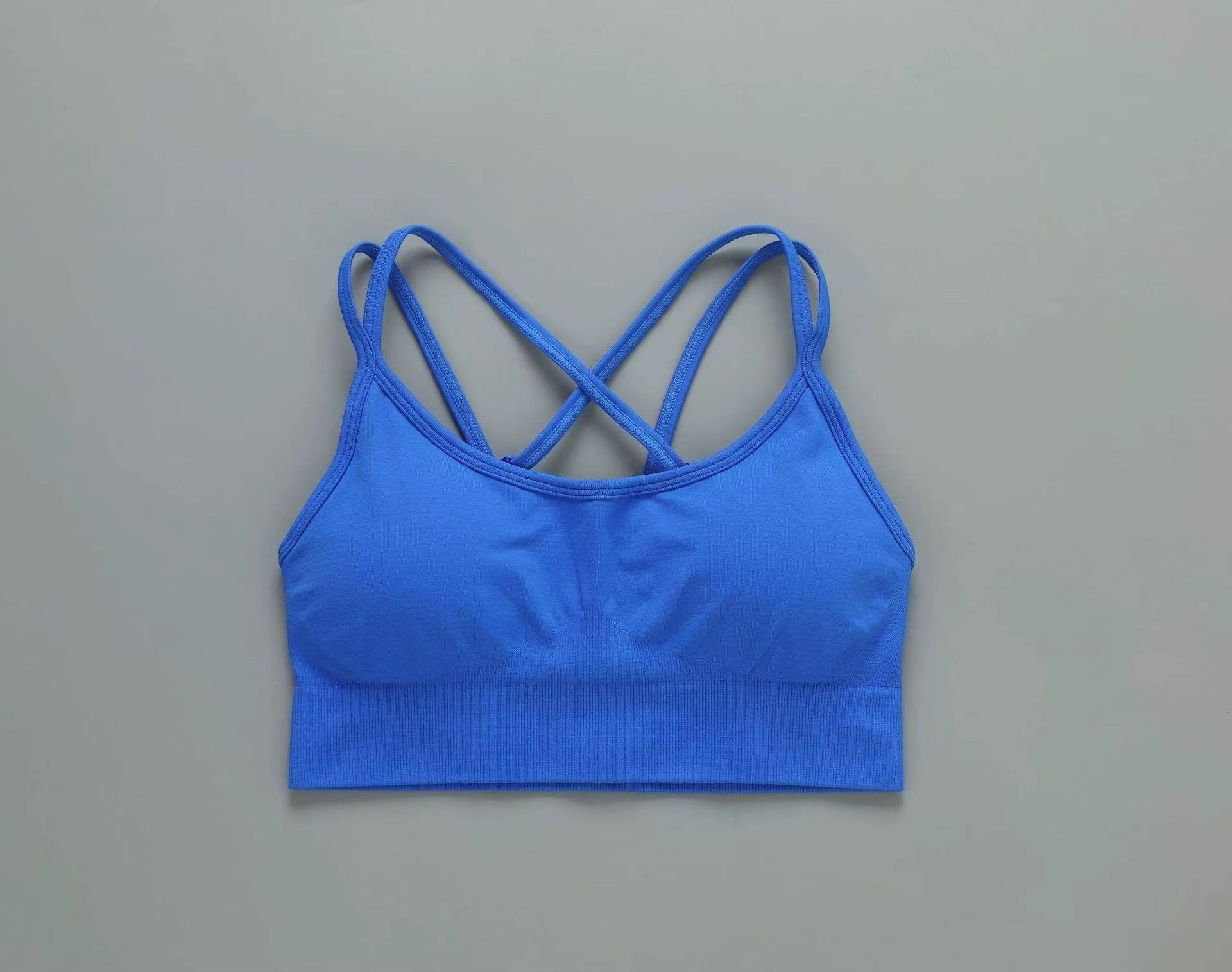 MotionMade blue push-up sports bra with cross-back straps and moisture-wicking fabric for yoga and gym workouts.