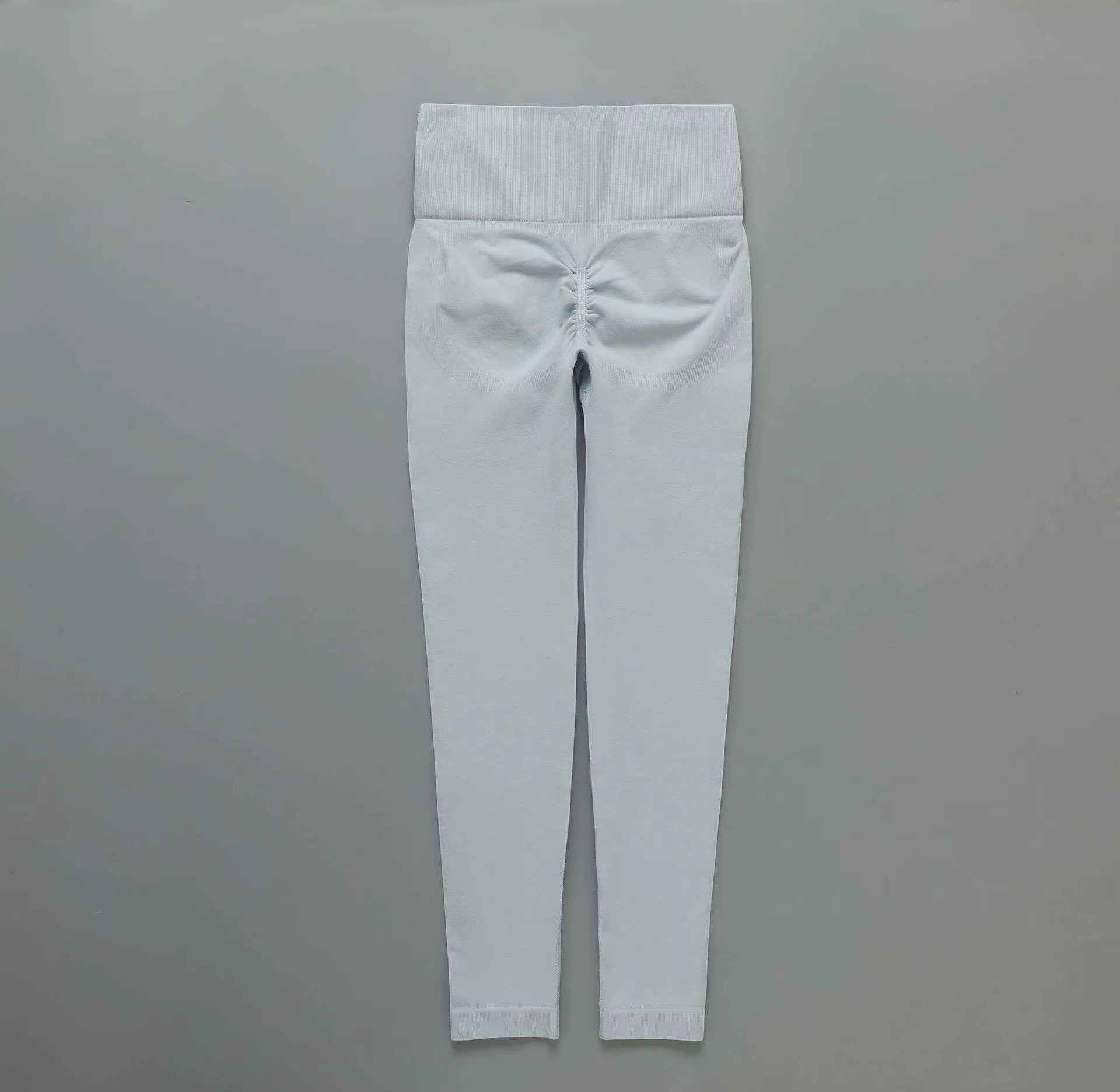 MotionMade light grey high-waisted seamless leggings with ruched push-up detailing for yoga and gym workouts.