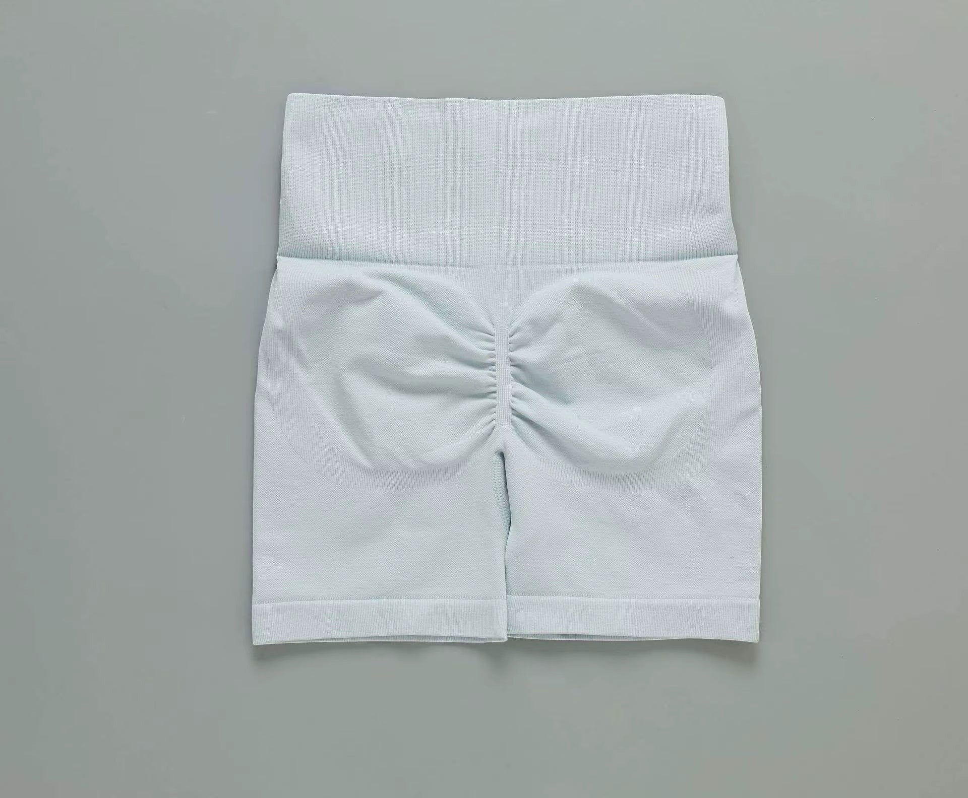 MotionMade light blue high-waisted seamless workout shorts with ruched push-up detailing for yoga and gym training.