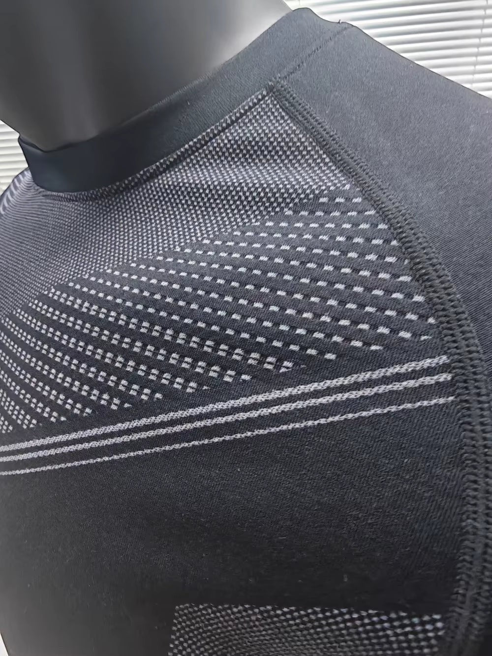 MotionMade black men's seamless compression shirt with textured body-mapping panels for athletic performance.