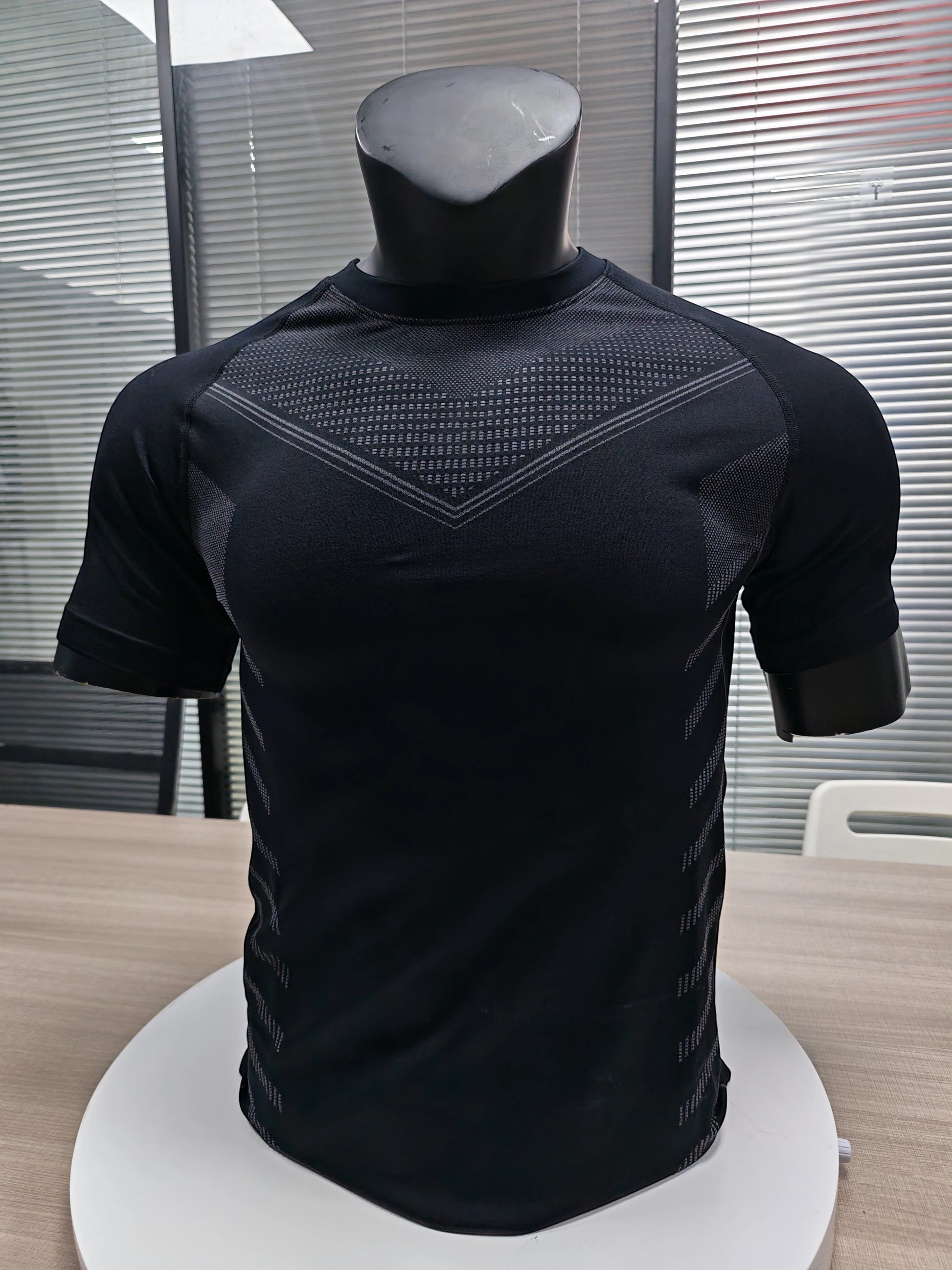 MotionMade black seamless compression shirt with body-mapping knit patterns for athletic performance and support.