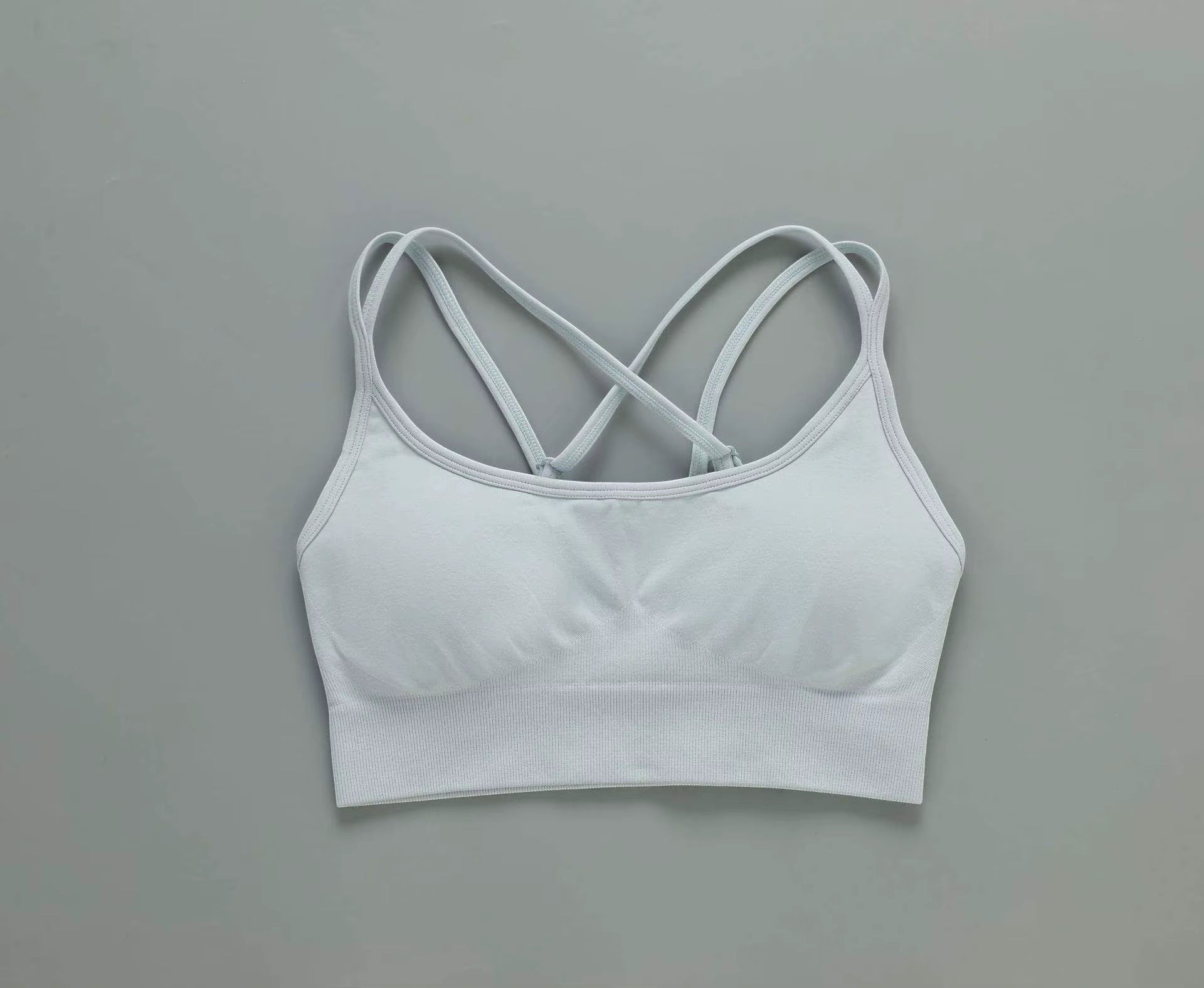 MotionMade light blue push-up sports bra with crisscross back straps, moisture-wicking fabric for yoga and gym.