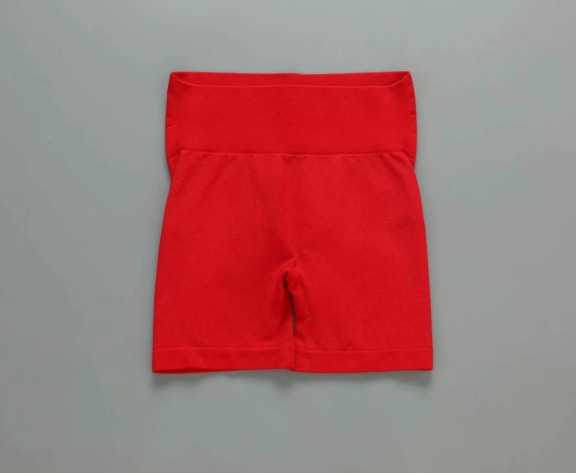 MotionMade red high-waisted seamless workout shorts with compressive waistband for yoga and gym training.