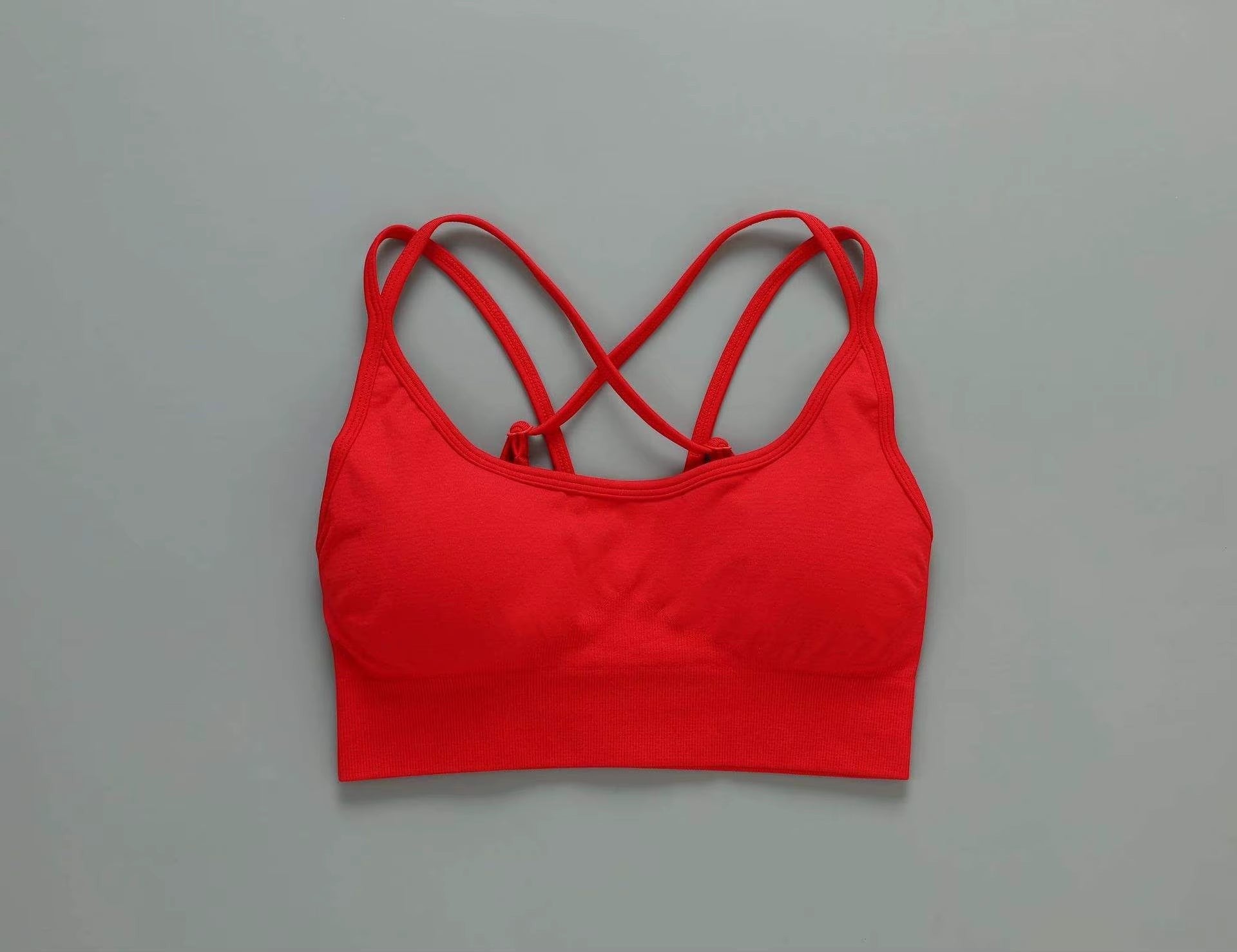 MotionMade red seamless push-up sports bra with crisscross back straps for yoga and gym workouts.