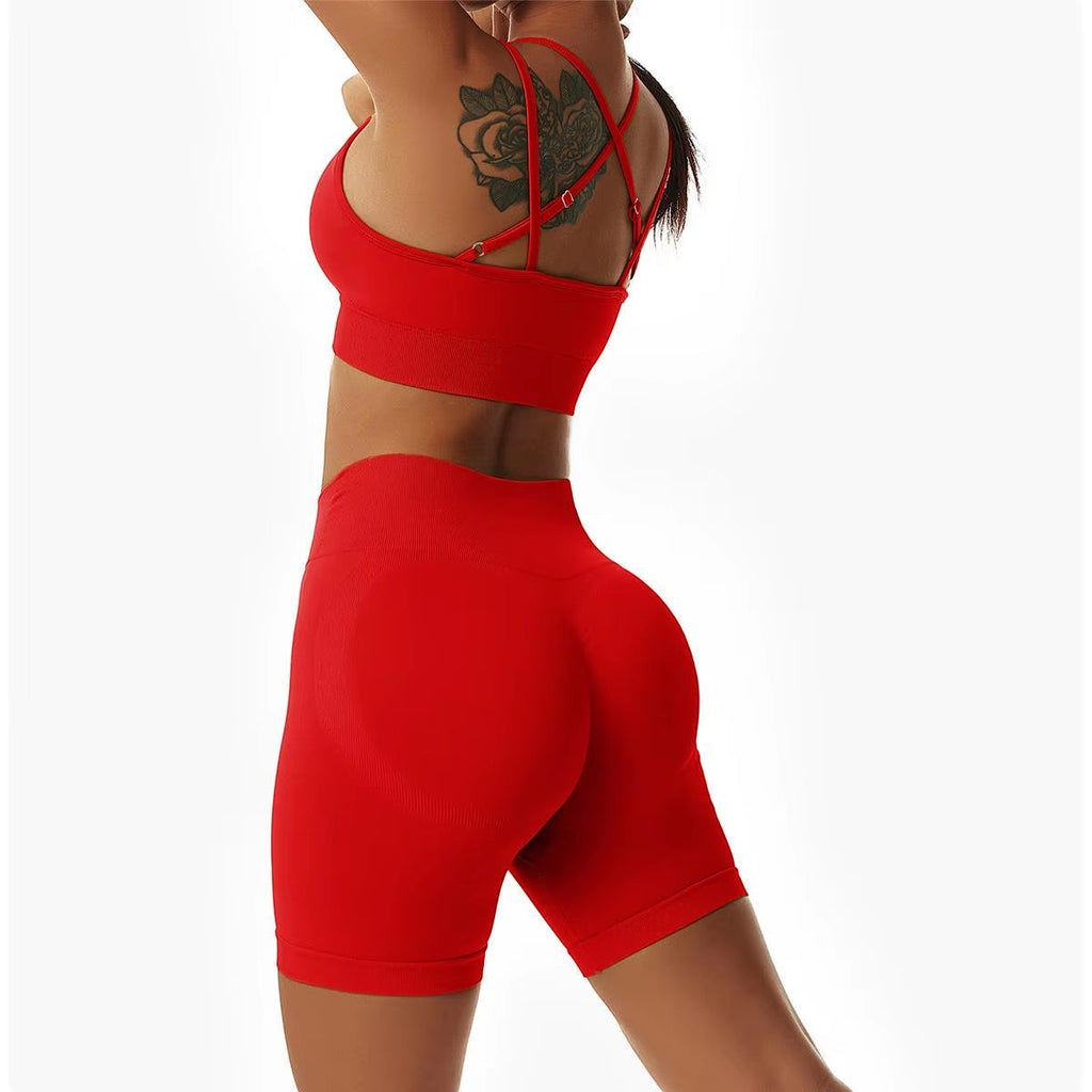 MotionMade red high-waisted workout shorts and push-up sports bra set with cross-back straps on a fit woman.