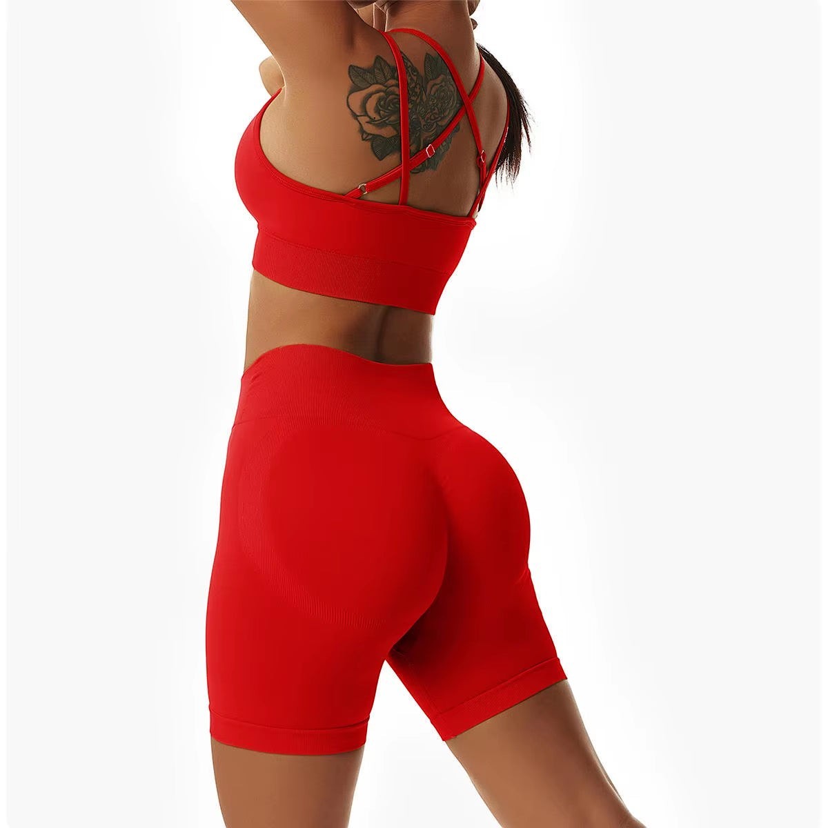 MotionMade red high-waisted workout shorts and push-up sports bra set with cross-back straps on a fit woman.