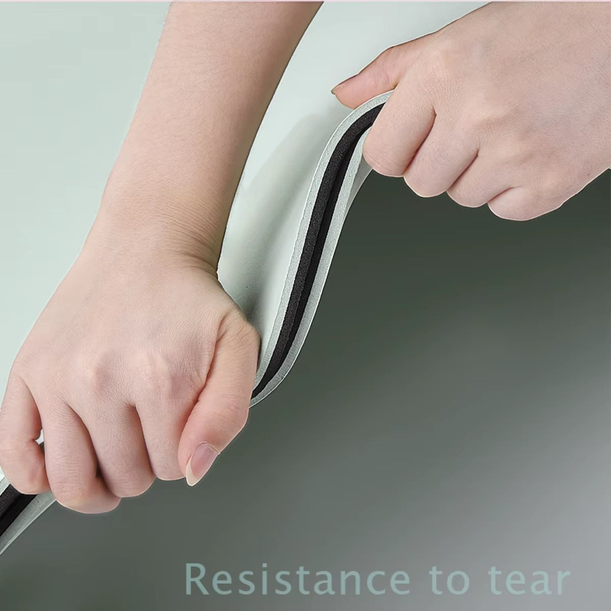 Hands testing the tear-resistant, dual-layer green and black MotionMade anti-slip yoga mat for durability.
