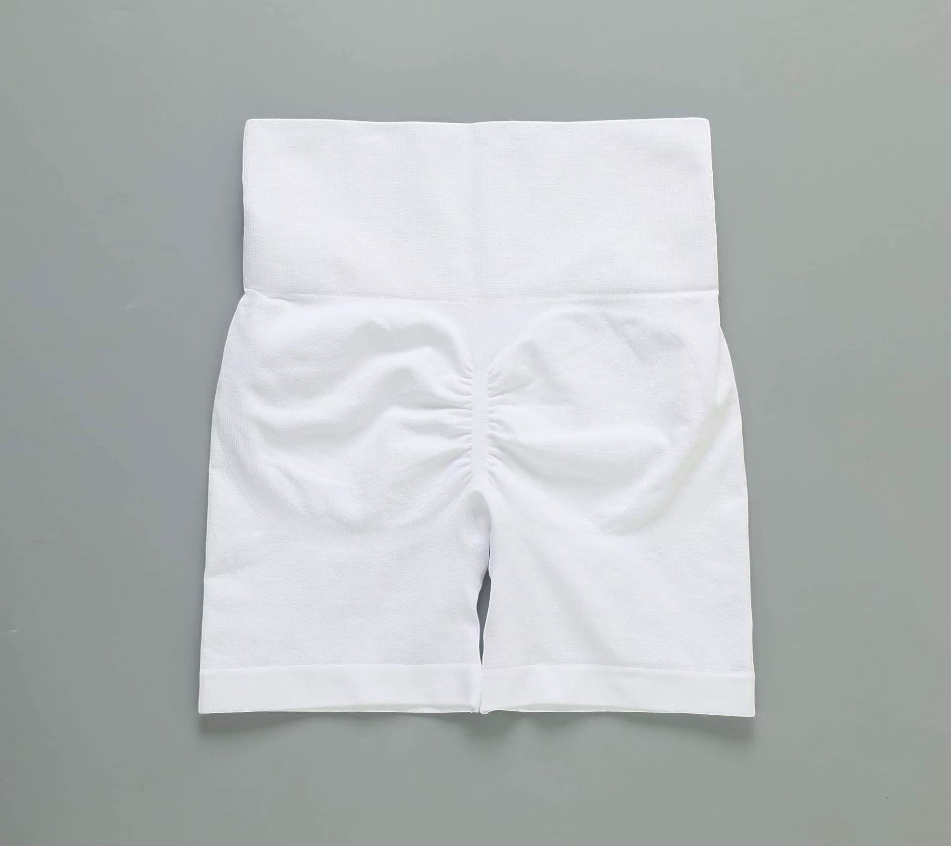 MotionMade white high-waisted workout shorts with push-up scrunch detail for gym, yoga, and fitness training.